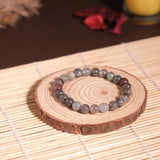 Beaded bracelet on a wooden coaster with a candle in the background