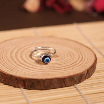 Silver ring with a blue evil eye on a wooden surface