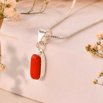 Silver necklace with a red coral pendant on a beige background