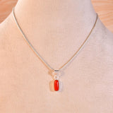 Necklace with a red coral pendant on a mannequin bust against an orange background