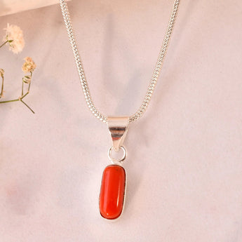 Silver necklace with a red coral pendant on a beige background