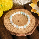 Multicolored beaded bracelet on a wooden surface with yellow flowers in the background