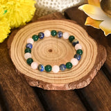 Multicolored beaded bracelet on a wooden surface with flowers in the background