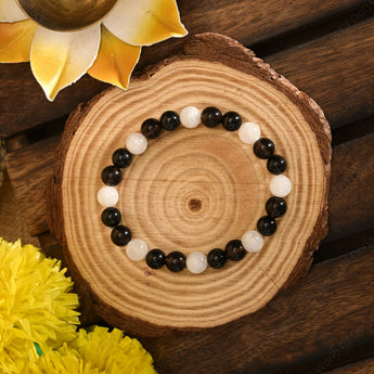 Black and white beaded bracelet on a wooden surface with yellow flowers