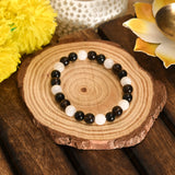Black and white beaded bracelet on a wooden surface with decorative elements.