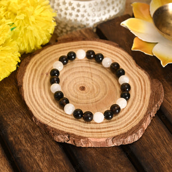 Black and white beaded bracelet on a wooden surface with decorative elements.