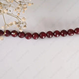 String of red beads on a white background with small white flowers.
