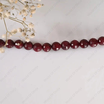 String of red beads on a white background with small white flowers.