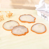 Set of four colorful crystal agate coasters arranged on a wooden tabletop