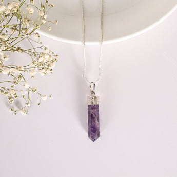 Amethyst crystal pendant necklace on a white background with small flowers.