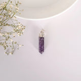 Purple crystal pendant on a white background with small flowers