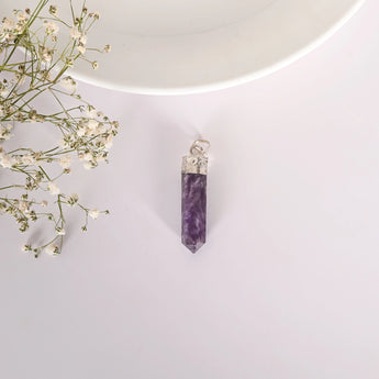 Purple crystal pendant on a white background with small flowers