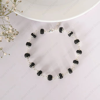 Black beaded necklace on a white background with a decorative plate and flowers.