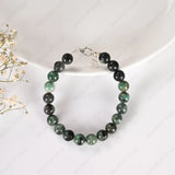 Beaded bracelet with green and black stones on a white background