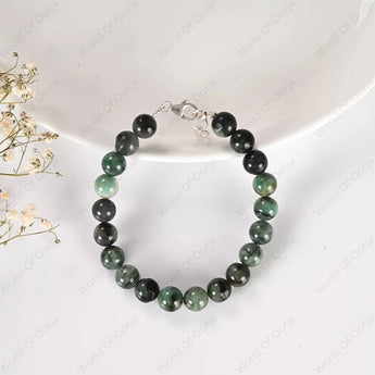 Beaded bracelet with green and black stones on a white background