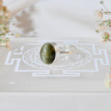 Silver ring with a cats eye stone on a burgundy fabric background
