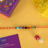 Colorful beaded Rakhi on a yellow background with a purple card and decorative box.