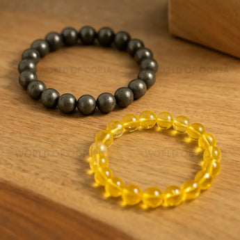Two beaded bracelets, one black and one yellow, on a wooden surface.