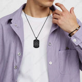 Person wearing a purple shirt with a white undershirt, black 7 chakra flower of life pendant on a light gray background