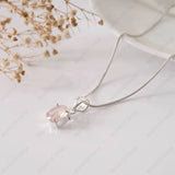 Silver necklace with a pink gemstone pendant on a light background
