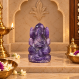 Amethyst Ganesh Ji murti in deep violet crystal on a marble altar with brass diya