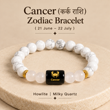 A Cancer zodiac bracelet made of white and gray marbled howlite and milky quartz beads, with a central black cube bead featuring a gold Cancer zodiac symbol and text. The bracelet is displayed on a beige textured pedestal with astrological text above and below.