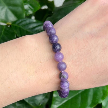Purple beaded bracelet on a wrist with a green leafy background