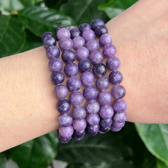Purple beaded bracelets on a wrist with a green leafy background