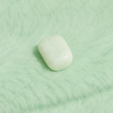 Jade tumble stone on a textured green surface