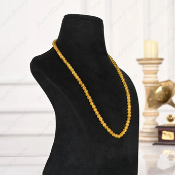 Gold necklace on a black mannequin bust with a blurred background
