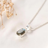 Labradorite pendant angled view — faceted oval stone with labradorescence