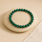 Malachite bracelet with deep green concentric banded beads on an off-white oval stone with ivory linen – World of Oorja