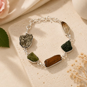 Raw Dhan Yog bracelet with uncut pyrite, tiger eye and quartz slabs on a silver chain, styled on a cream stone – World of Oorja