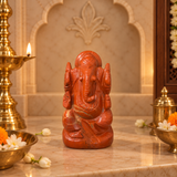 Red Jasper Ganesh Ji murti in deep brick red on a marble altar with brass diya