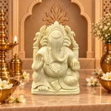 Serpentine Ganesh Ji murti in soft ivory-green stone on a marble altar with brass diya