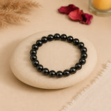 Shungite bracelet with opaque black beads and grey-green sheen on a cream river stone with pampas and rose petals – World of Oorja