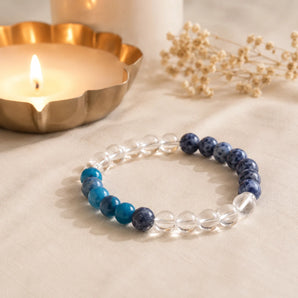 Weight Loss bracelet with clear quartz, teal blue apatite and navy sodalite beads on cream linen with a lit brass diya – World of Oorja